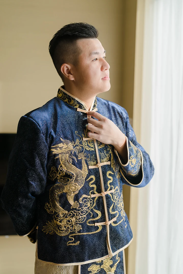 新郎在窗邊整理中式禮服