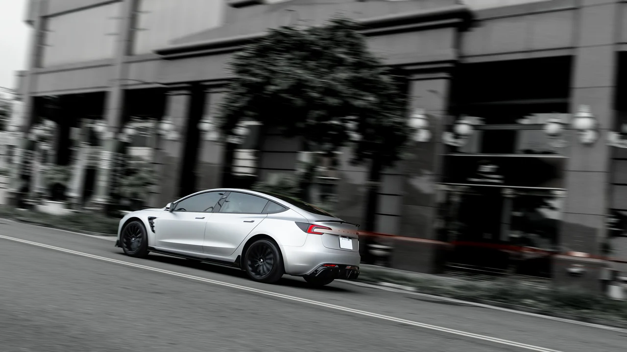 街景流動間，Tesla Model 3 的車尾與紅色尾燈